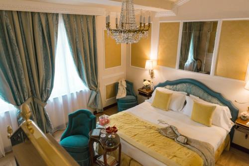 佛罗伦萨伯尼尼宫酒店的一间卧室配有一张床、一把椅子和一个吊灯。