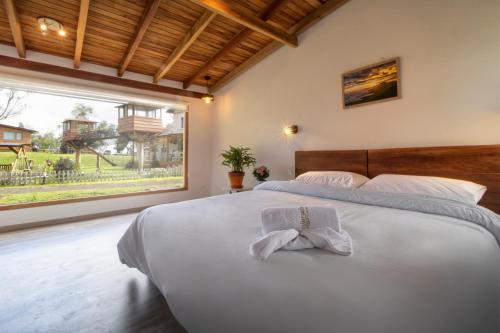 Machachi帕帕加科托帕希宾馆的卧室设有一张大白色的床,卧室设有大窗户