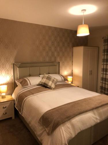 MaudBruxie Holiday Cottages - Honeysuckle Cottage的一间卧室配有一张带两盏灯的大型白色床。