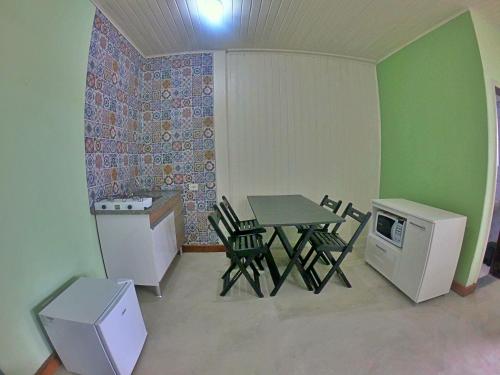 圣保罗Kitnet Com Ar, em frente a Praia de Boracéia的小房间设有桌椅和冰箱