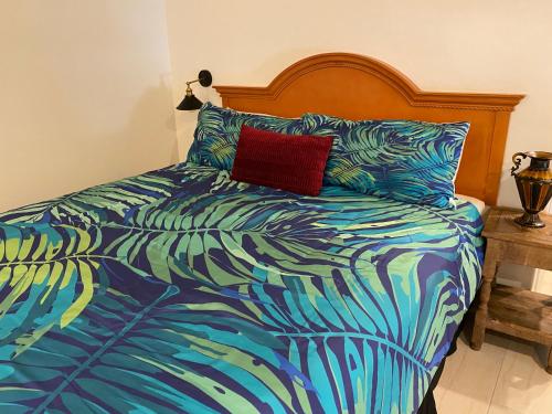 圣巴巴拉玫瑰别墅旅馆的一张带五颜六色的棉被和红色枕头的床