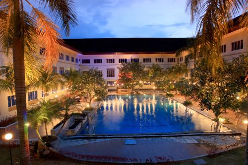 丹戎槟榔ASTON Tanjung Pinang Hotel & Conference Center的棕榈树建筑中间的大型游泳池