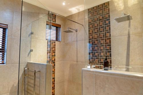 Op-die-BergBoplaas Guesthouse的带淋浴的浴室和玻璃门