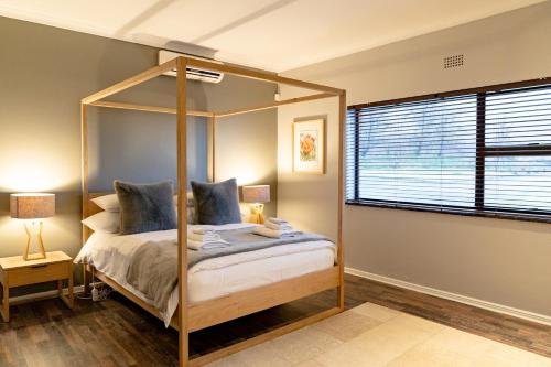 Op-die-BergBoplaas Guesthouse的一间卧室设有天蓬床和窗户。