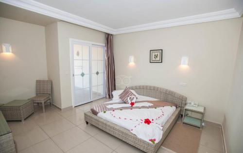 杰尔吉斯乐拉梅里亚姆酒店及俱乐部的一间卧室配有白色床单和红色鲜花。