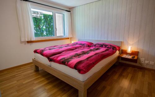 NiederriedFerienwohnung Selinda的一间卧室配有一张带粉色床单的床和一扇窗户。