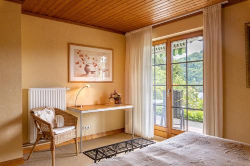 埃恩鲁赫Ferienwohnung-Mediterran的一间卧室配有一张床、一张书桌和一个窗户。
