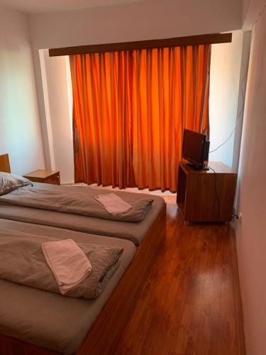 TituHOTEL modern / Imobiliare Garcea Titu的一间卧室配有两张床和橙色窗帘