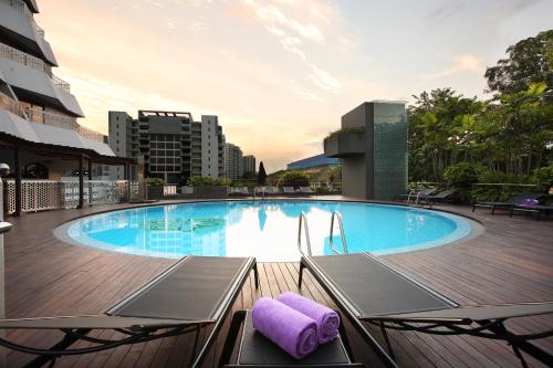新加坡Village Hotel Katong by Far East Hospitality的一个带两把椅子和一条紫色毛巾的大型游泳池