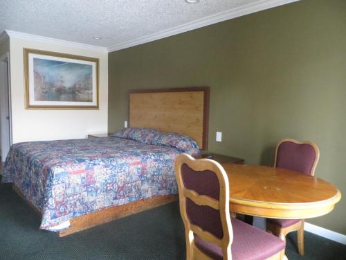 安纳海姆加登格罗夫国家旅馆的卧室配有一张床和一张木桌及椅子
