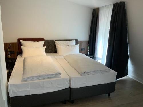 富尔达Altstadthotel Arte的卧室内的一张带白色床单和枕头的床