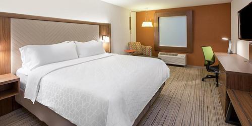 代顿Holiday Inn Express & Suites Dayton North - Vandalia, an IHG Hotel的酒店客房设有一张大床和一张书桌。