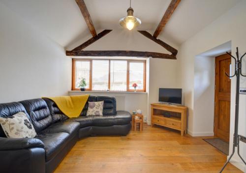 BerriewSmithy Cottage的客厅配有黑色真皮沙发和电视