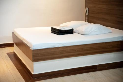 坎皮纳斯Prime Motel Campinas的一张带白色床垫和黑色手提箱的床