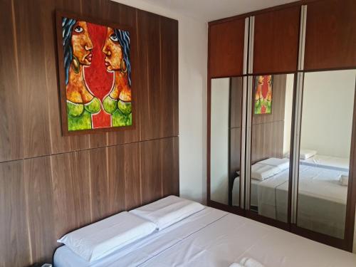 戈亚尼亚Morro Vermelho的卧室配有一张床,墙上挂有绘画作品