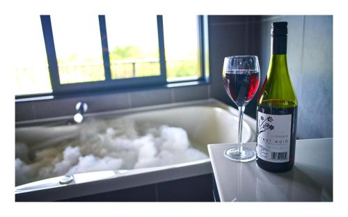 格雷默斯Luxury Seaview Apartments的一瓶葡萄酒,坐在带玻璃的浴缸旁