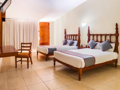 韦拉克鲁斯Collection O Hotel Mocambo, Boca del Río的一间卧室配有两张床、一张桌子和一张书桌