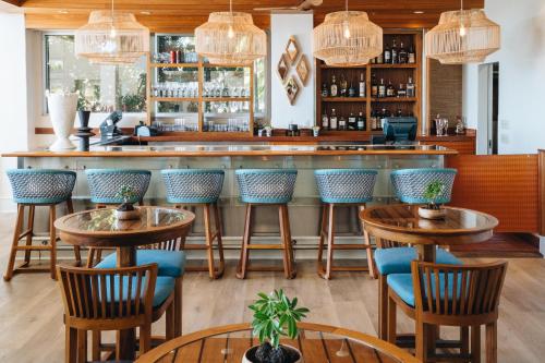檀香山Kaimana Beach Hotel的酒吧配有木桌和蓝色椅子