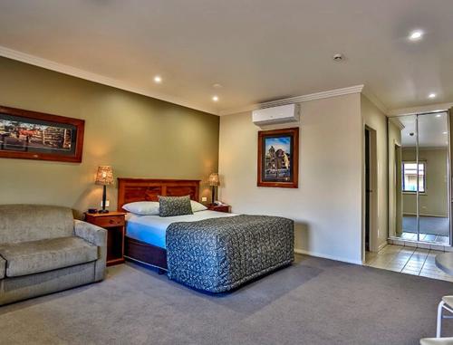 海伊绍布什汽车旅馆的一间卧室配有一张床、一张沙发和一把椅子