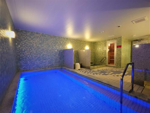 宫崎Green Rich Hotel Miyazaki Tachibandori 2 (Artificial hot spring Futamata Yunohana)的客房内的大型游泳池拥有蓝色的灯光