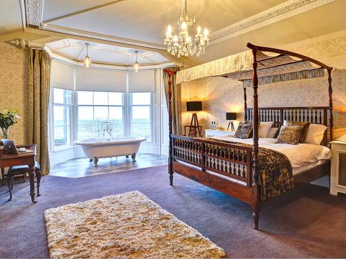 格兰奇奥沃桑茨海湾别墅住宿加早餐旅馆的一间带一张天蓬床和浴缸的卧室以及一间带吊灯的卧室。
