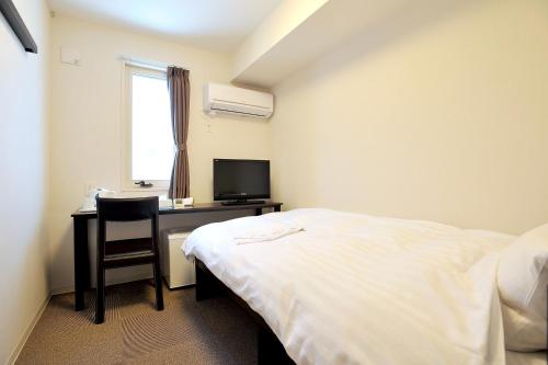 石卷市石卷价值酒店的一间卧室配有一张床和一张书桌及电视