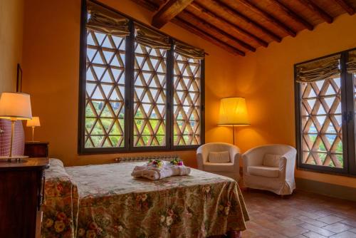 佩萨河谷塔瓦内莱Podere Vigliano的一间卧室配有一张床、两把椅子和窗户