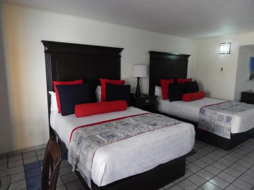 卡波圣卢卡斯Studio At Marina Los Cabos的两张位于酒店客房的床,配有红色和蓝色枕头