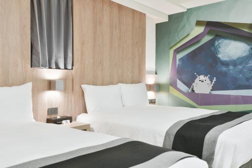 台中市传思文旅的酒店客房,配有两张床和一幅画