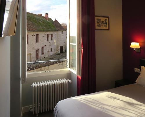 Mehun-sur-YèvreHôtel Le Dormeux的一间卧室设有窗户、一张床和散热器