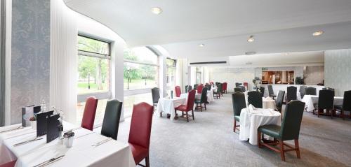 格里姆斯比St James Hotel的用餐室配有白色的桌子和红色的椅子
