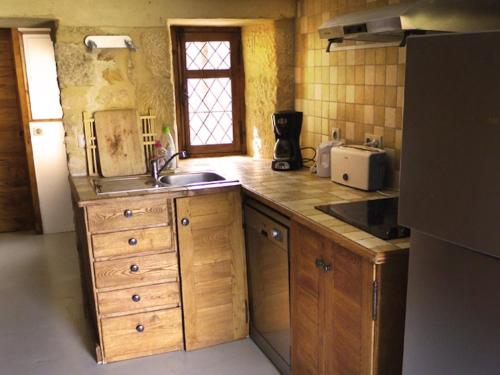 贝纳克和卡泽纳克Maison Linol的厨房配有木制橱柜、水槽和窗户。