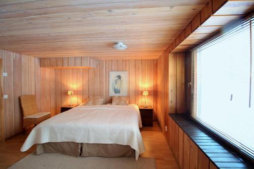 罗瓦涅米Villa Talo的一间卧室配有一张带木墙和窗户的床。