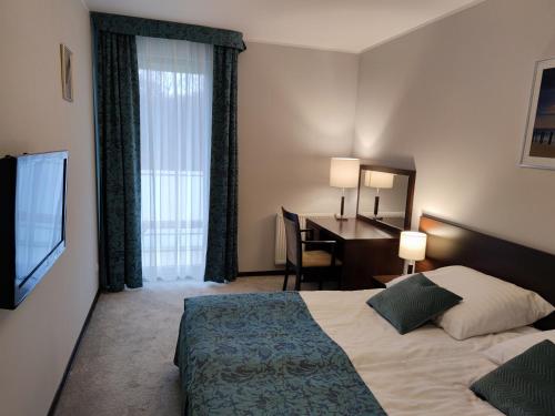 科沃布热格Apartament przy hotelu Aquarius的酒店客房配有一张床、一张书桌和一台电视。