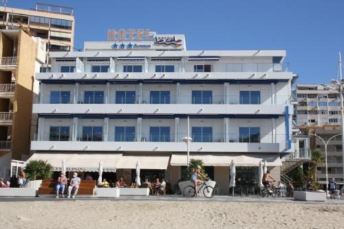 卡拉德费斯特拉特Hotel La Cala Finestrat的海滩上有人坐在酒店前面的酒店