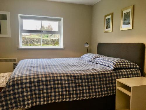 KinbuckWoodside Cottage Self Catering的一间卧室配有一张带铺着地毯的床和窗户。