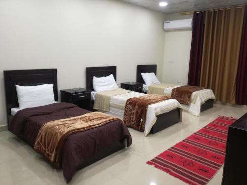 瓦迪穆萨Petra Crystal hotel的酒店客房,设有三张床和红色地毯