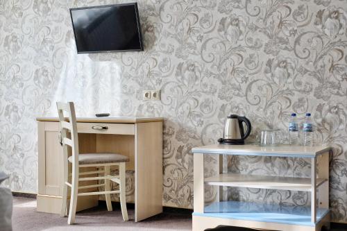 埃斯托萨多克Альпийская сказка Плюс的客房设有一张桌子、一把椅子和一台墙上的电视