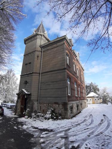 韦尔维耶克雷美小屋住宿加早餐酒店的一座有塔的旧建筑,雪中