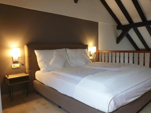 布尔格-罗伊兰德霍汗布施酒店的一间卧室配有一张带两盏灯的大型白色床。