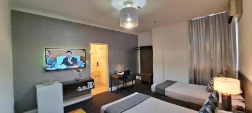 珀斯珀斯标准酒店的一间酒店客房,配有一张床和一台墙上的电视