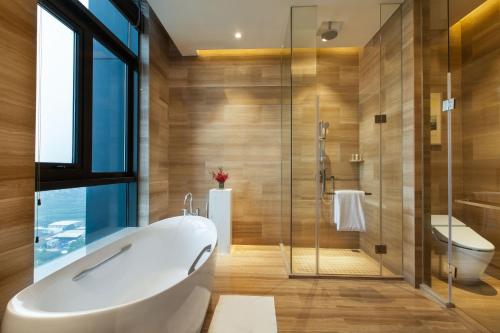 莆田莆田秀屿假日酒店的带浴缸和玻璃淋浴间的浴室。
