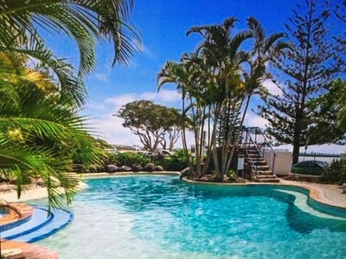 卡伦德拉Just Perfect Apartment with Ocean Views的一个带滑梯和棕榈树的游泳池