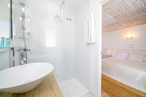 圣安东尼奥Can Beia Hostal Boutique的白色的浴室设有浴缸和床。