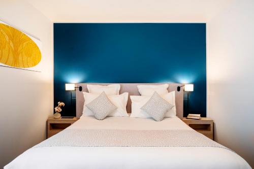 圣旺Residhome Saint Ouen的一间卧室配有一张带蓝色床头板和枕头的床。
