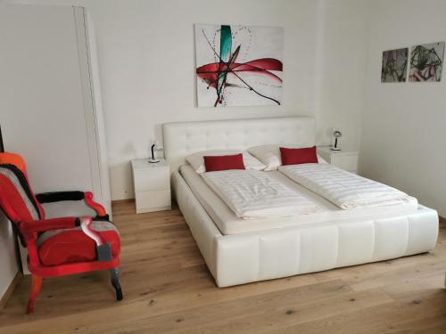 PulkauSchneiders Ferienhaus Pulkau的卧室配有白色的床和红色椅子