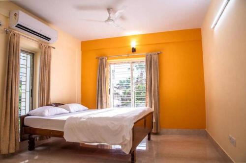 加尔各答Diamond By Olys Apartment的一间卧室设有一张黄色墙壁和窗户的床