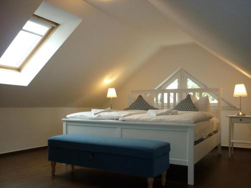 巴斯托夫Pension Dachgeschosswohnung的卧室配有白色的床和蓝色的搁脚凳