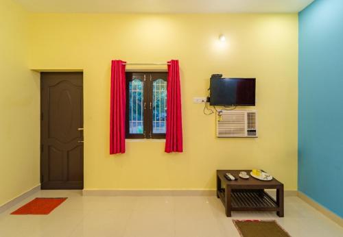 蓬蒂切里Aashikha Farm House的一间设有门的房间和一个带红色窗帘的窗户