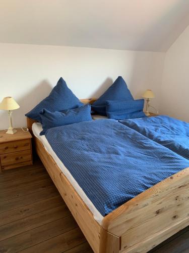 UphusumFerienwohnung_25的一间卧室配有一张带蓝色床单和枕头的木制床。